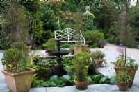 A small pond with water fountain, surrounded by pots in the Northern Summerhouse Garden - The Lost Gardens of Heligan in Cornwall