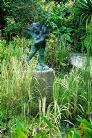 A water feature statue in the Italian Garden with pond and grasses - The Lost Gardens of Heligan in Cornwall