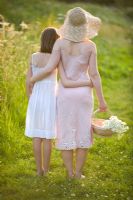 Woman and girl walking in evening summer sunlight, carrying a trug of picked flowers