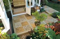 Sophisticated timber deck made with individual deck squares laid to form a diamond pattern around a newly installed conservatory