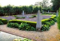 Formal geometric garden with stone obelisks and balls, planted with Lavandula, Buxus and Bergenia 