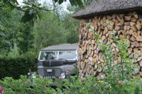 Wood storage and Land Rover in country garden, Holland