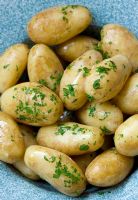 Cooked potatoes with butter and parsley in a blue bowl