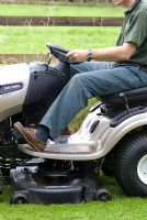 Man on a ride on lawn mower in July