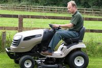 Man on a ride on lawn mower in July