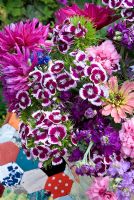 Colourful cut summer flowers in bucket on patchwork tablecloth - Dahlias, Zinnias, Mattiola incana, Nigella, Dianthus barbartus 
