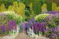The herbaceous long border with an arch in the tapestry hedge - Town Place Garden, Sussex
 