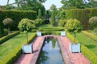Reconstruction of an Eighteenth Century canal garden. Lollipop trained citrus trees growing in Versailles tubs around pond. The Dower House, Morville Hall Gardens
 