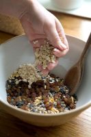 Adding oats to a mixing bowl of ingredients to make seed cakes for wild birds
