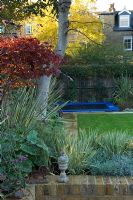 Contemporary urban garden with lighting, sunken trampoline and raised bed - London