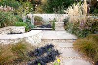 Modern garden in late summer with plantings of Carex testacea and Ophiopogon planiscapus 'Nigrescens' 