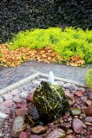 Fountain spout. Borders of Fagus sylvatica 'purpurea', Alchemilla mollis and Heuchera 'Caramel'