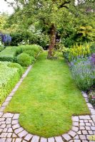 Small formal lawn in country garden with a granite sett edging