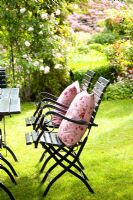 Metal chairs on lawn in country garden