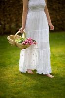Woman wearing a white dress carrying a trug of Tulips