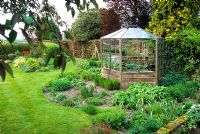 Octagonal cedarwood greenhouse and informal herbaceous beds in spring