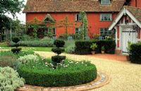 The courtyard in summer with clipped Buxus - Box circles, Taxus - Yew topiary and Osteospermums