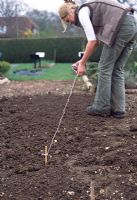 Sowing grass seed over the patch and rake lightly to cover some of the seeds - Marking out a line