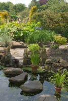 Stepping stones over pool, leading to path and herbaceous borders in June at Broughton House garden, owned by The National Trust for Scotland
