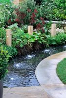 Circular rill with copper water spouts fixed in timber pillars - RHS Malvern Spring Gardening Show