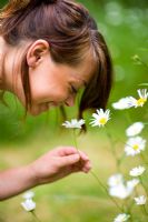 Woman smelling daisies in the garden