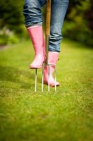 Woman wearing pink wellies and jeans, using a garden fork