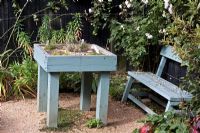 Wooden table planted with herbs and bench in the Herb Garden, Barnsdale Garden