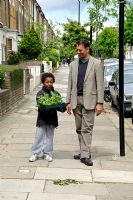 Little boy with his father carrying a tray of plants in an urban street in Hackney, London