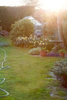 Glass greenhouse and spring border at sunset at  Waders, Sussex