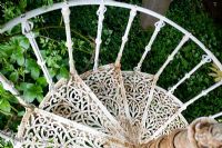 Decorative metal spiral staircase leading down from canopy treehouse. Chauffeurs Flat, Surrey