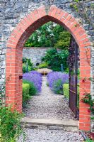 View through Archway of Lavandula angustifolia 'Munstead' in walled vegetable garden - Sedbury Park Secret Garden, Orchard House, Sedbury Park, Monmouthshire. 