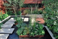 Water garden with floating York Stepping stones. Moisture loving plants in a rusty metal container in shallow water. Veronicastrum album, Stipa, Hosta and Ferns. 'Urban Serenity' - Gold Medal Winner - RHS Hampton Court Flower Show 2010 
 