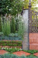 Rainbow effect water feature next to herringbone tile steps, leading up to a carved wooden gate.  Plants include Lavandula angustifolia 'Alba' Koeleria glauca, Armeria maritima 'Alba' and clipped Ligustrum. 'The Garden Lounge' - Silver Gilt Medal Winner - RHS Hampton Court Flower Show 2010 
 