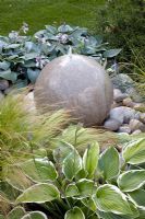 Round stone water feature amongst Hosta and Stipa tenuissima - The Urban Retreat, Bronze medal winner at RHS Hampton Court Flower Show 2010