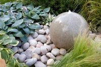 Round stone water feature amongst Hosta and Stipa tenuissima - 'The Urban Retreat', Bronze medal winner, RHS Hampton Court Flower Show 2010 