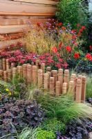 Verbena bonariensis, Achillia 'Red Velvet', Sedum and Miscanthus, decorative timber stumps as a low dividing wall - Tatton Park Flower Show 2010
