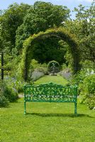 Ornate metal seat looking towards armillary sundial through rose arch and adjacent Nepata borders - Kellie Garden, Fife, owned by The National Trust for Scotland