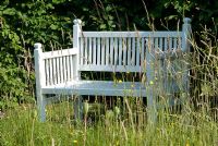 White bench in meadow, backed by Carpinus betulus - Young hornbeam hedge at Heveningham, Suffolk