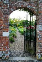 Gateway into the walled kitchen garden reveals the double herbaceous borders. Edmondsham House, Cranborne, Wimborne Minster, Dorset, UK