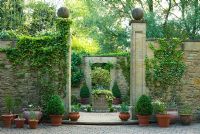 Entrance to a small formal 'antechamber' to walled garden, built 1999, designed by late Graham Hopewell, planted with a combination of cool evergreens including low hedges of Hedera 'Ivalace', clipped box and standard holly - Mill House, Netherbury, Dorset
