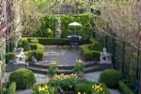 Elevated view of urban formal garden in Spring with terrace and clipped Buxus - Box parterre planted with Tulipa 'Yellow Purissima', Tulipa 'Jan Siemerink', Tulipa 'Ivory Floradale' 
