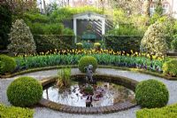 Formal garden with circular pond, beds of Tulipa 'Washington' and Tulipa 'Juliette' and clipped box balls 