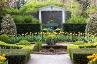 Formal garden with circular pond, beds of Tulipa 'Washington' and 'Juliette' and clipped Buxus - Box balls 
 