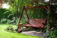 Wooden swinging bench in shadey area