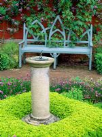 The herb garden with sundial underplanted with Origanum vulgare 'Aureum' and chives at Wyken Hall, Suffolk
