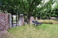 Deckchairs on lawn with trees, pruned conifers and grasses - Hobrede, Holland