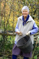 Leonie Woolhouse working in her garden, collecting dried seed pods - Owner of The Old Sun House, Wymondham, Norfolk, NGS 