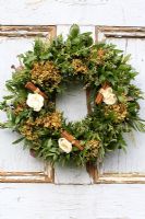 Christmas wreath made with dried Hydrangea flowers, roses and cinnamon sticks, hanging from rustic door