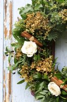 Christmas wreath made with dried Hydrangea flowers, roses and cinnamon sticks, hanging from rustic door
