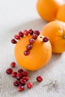 Making a Cranberry and Orange pomander for Christmas -  putting the cranberries on the orange using dressmaking pins